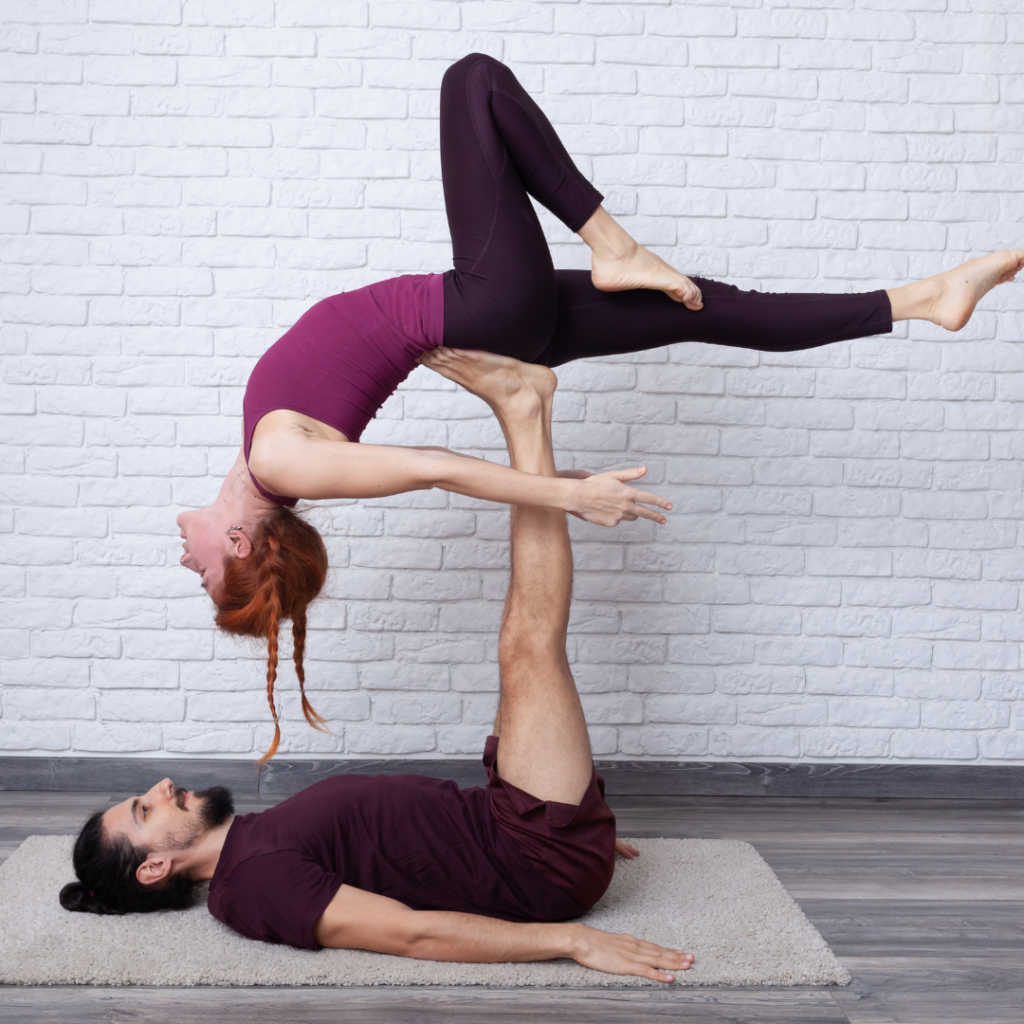 two people doing an acroyoga pose in front of a white brick wall