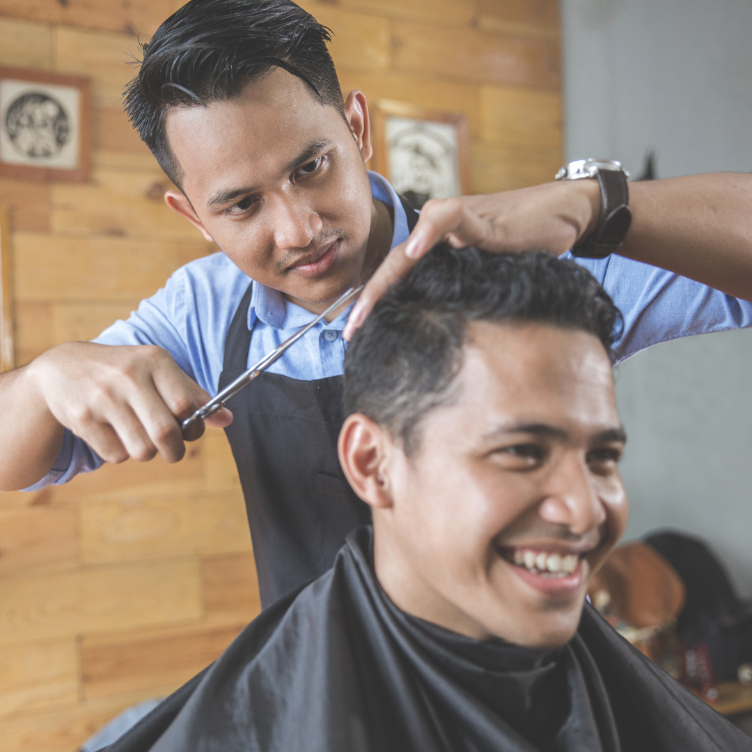 a person is cutting another person's hair in a barber shop