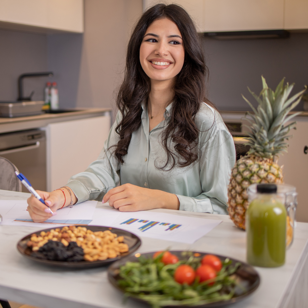 a nutritionist sitting at a kitchen table with fruit and vegetables