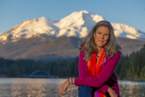 Headshot of Joy Taylor with mountain range and lake in background