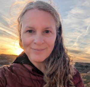 headshot of Camille, smiling with the sun in the background