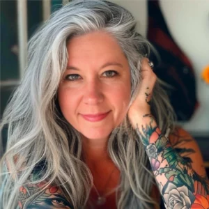 Gina Fox headshot, smiling with arm on resting on face