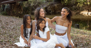 Corina Fitch, smiling with three young girls on a blanket