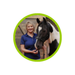 photo of April Love smiling with a blue shirt, holding the reigns of a black and white horse