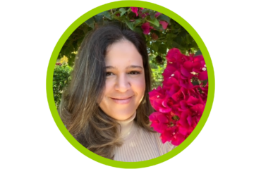 Elisa Calosso Elisa Calosso in brown shirt with hair to one side, smiling with no teeth with a background of pink flower tree